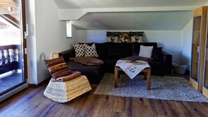 En hyggelig stue med en sofa, en fletstol, et sofabord og en tæppe med et mønster.