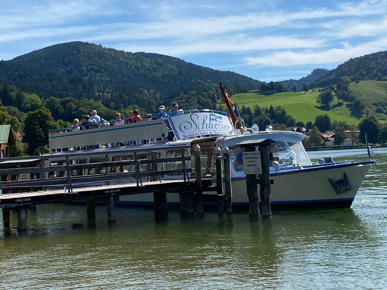 Ein Boot liegt an einem Steg vor einer Bergkulisse.