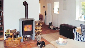 A cozy living room with a wood-burning stove, a stone fireplace, a dog, and a window with a view. - Stunning home in Linderöd with WiFi (Linderöd)