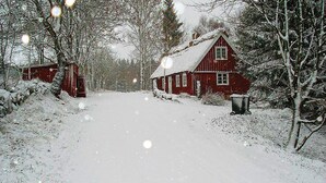 A snow-covered path leading to a red wooden house with a chimney, surrounded by snow-laden trees. - Stunning home in Linderöd with WiFi (Linderöd)