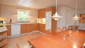 A modern kitchen with wooden cabinets, a built-in microwave, and a dining area with a wooden table and chairs. - 5 bedroom amazing home in Væggerløse (Væggerløse)