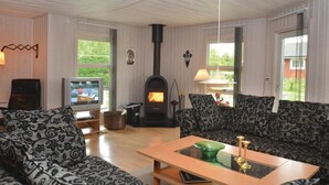 A cozy living room with a fireplace, patterned sofas, a television, and a wooden coffee table. - 5 bedroom amazing home in Væggerløse (Væggerløse)