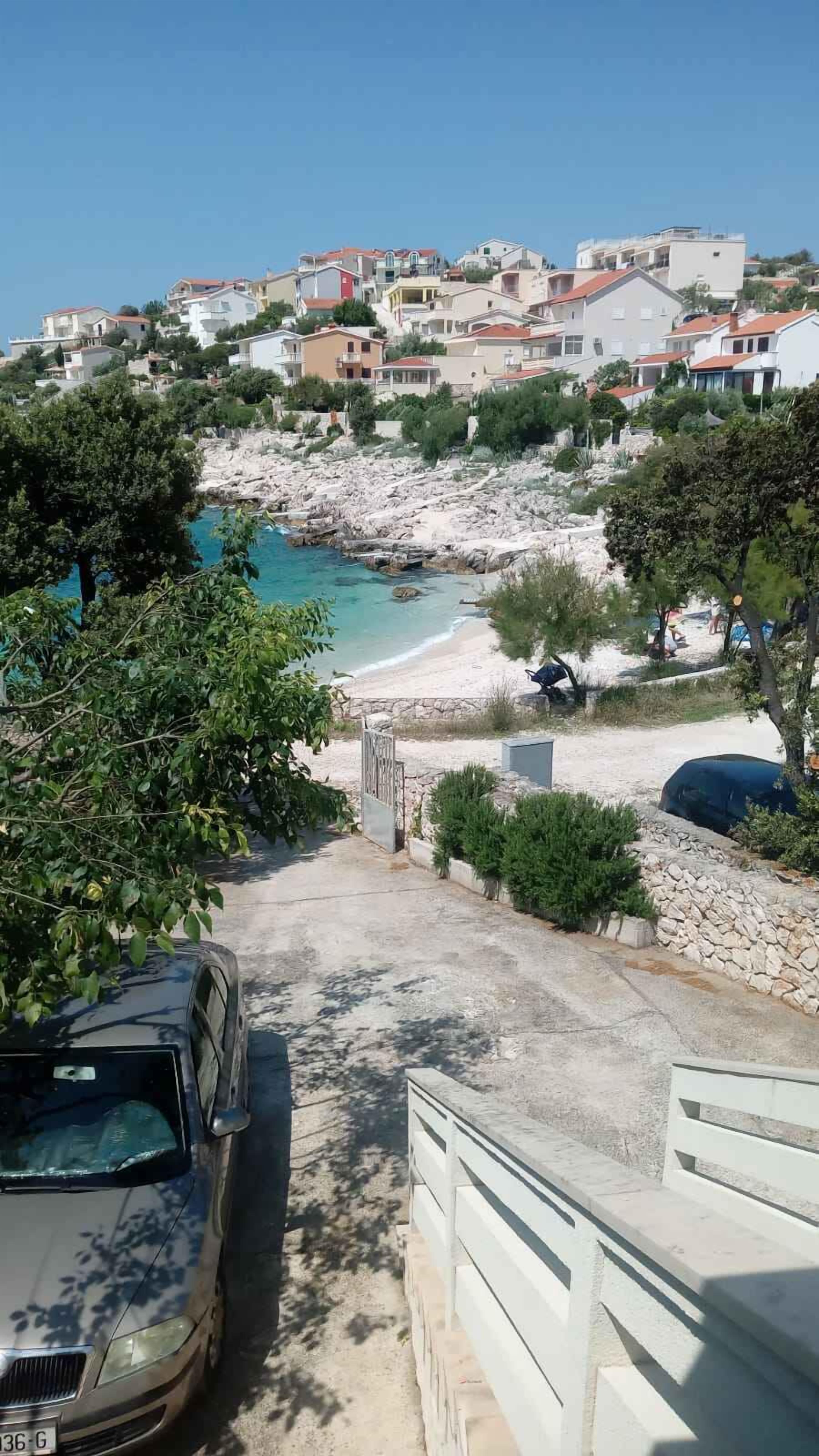 A coastal road leading to a beach with houses in the background.