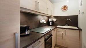 A modern kitchen with wooden cabinets, a built-in oven, a coffee maker, and a sink. - Apartment 3 - Apartments Lohbinder (Fam. Holzer) (Rottach-Egern)