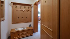 A hallway with a wooden wardrobe, a wooden dresser, and a door with a number. - Apartment 3 - Apartments Lohbinder (Fam. Holzer) (Rottach-Egern)