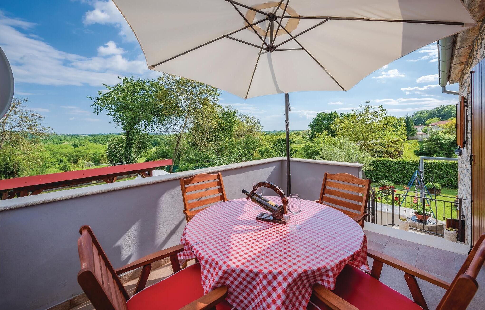 A balcony with a table and chairs, a wine bottle, and a checkered tablecloth.