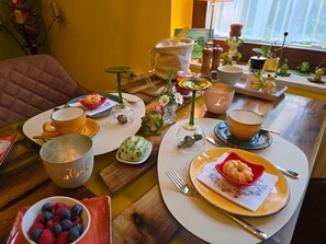 A dining table set with various dishes, a coffee cup, and a decorative frog figurine. - Single Room - Pension Max (Senftenberg)
