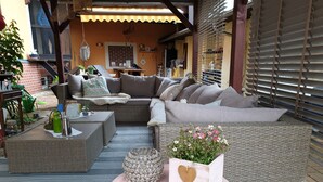 A cozy outdoor seating area with a wicker sofa, a round table, and a decorative planter. - Single Room - Pension Max (Senftenberg)