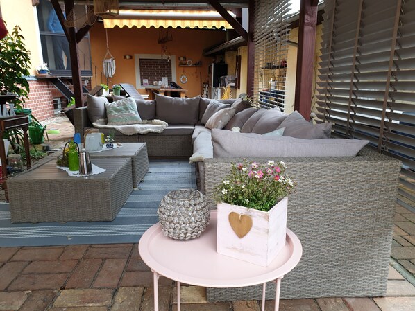 A cozy outdoor seating area with a wicker sofa, a round table, and a decorative planter.
