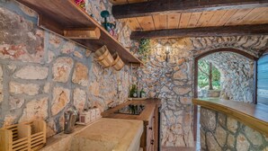 A stone-walled bar area with wooden shelves and a rustic ceiling.