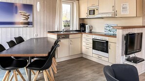 Cocina compacta con comedor, microondas, horno y televisor de pantalla plana.