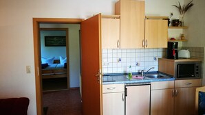 Une cuisine compacte avec des meubles en bois, un four à micro-ondes, un grille-pain et un évier.