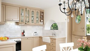 A kitchen with beige cabinetry, a white countertop, a built-in oven, and a dining area with white chairs and a table. - House to the lighthouse by A&M - House to the lighthouse (Kampen (Sylt))