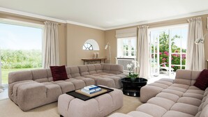 A spacious living room with a large sectional sofa, a coffee table, and a view of a garden through large windows. - House to the lighthouse by A&M - House to the lighthouse (Kampen (Sylt))