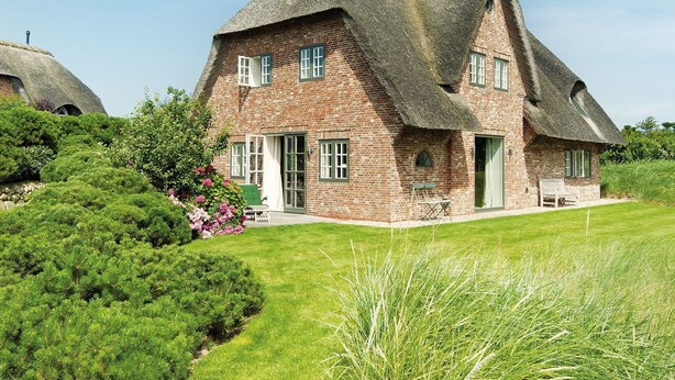 A traditional brick house with a thatched roof, surrounded by well-maintained hedges and a lawn. - House to the lighthouse by A&M - House to the lighthouse (Kampen (Sylt))