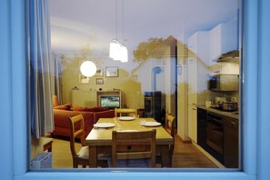 A modern kitchen with a dining area, a TV, and a refrigerator.