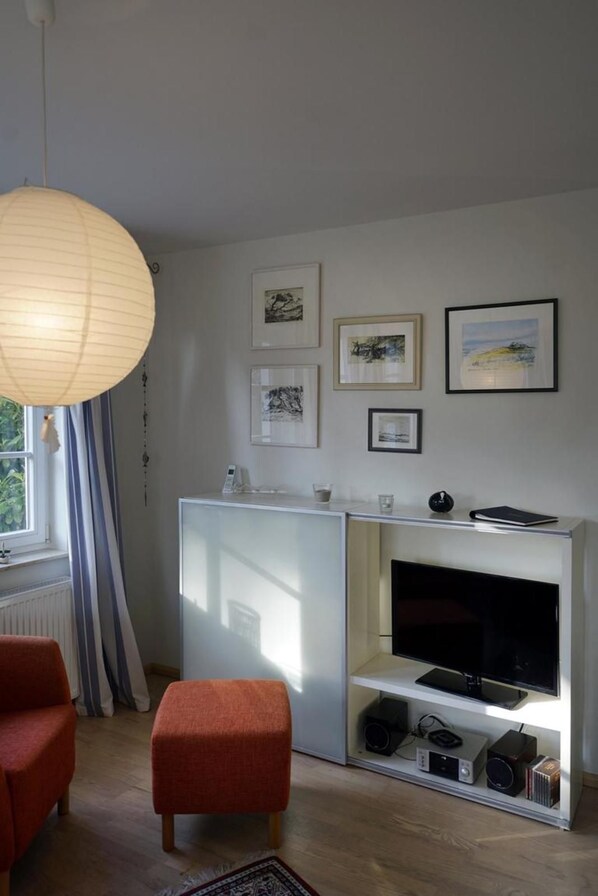 A modern living room with a white entertainment unit, a flat-screen TV, and framed artwork on the wall.