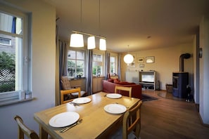 A dining area with a wooden table, chairs, and a TV in the background. - Hagens Hus - Hagens Hus (Prerow)