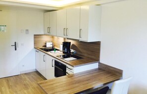 A compact kitchen with white cabinets, a wooden countertop, a coffee maker, and a toaster.