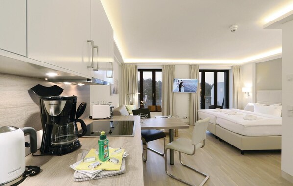 A hotel room with a kitchenette, a dining area, and a bed.
