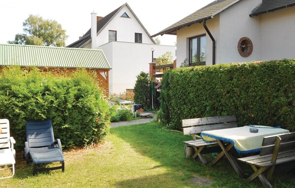 Ein Garten mit einem Holztisch, Stühlen, einer Holzbank und einem Hecken.