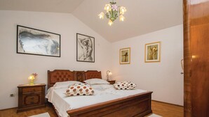 Une chambre à coucher avec un lit en bois, deux tables de chevet, un lustre et trois œuvres d’art encadrées accrochées au mur.