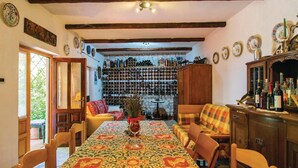Un coin repas avec une nappe à motifs, des chaises en bois, un canapé et un meuble à vin en arrière-plan.