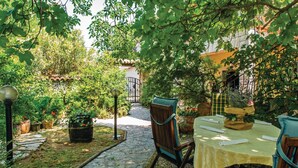 Une terrasse extérieure avec un sol en pierre, une table recouverte d’une nappe jaune et des chaises.