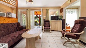 Un salon avec un canapé, une table basse, un téléviseur et un fauteuil.
