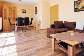 Sala de estar com sofá marrom, mesa de centro de madeira e área de jantar com cadeiras e um armário.