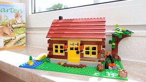 LEGO-talo, jossa on punainen katto, keltainen ovi ja ikkunat.