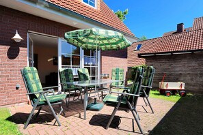 A patio with four green and white striped chairs, a table, and a green and white striped umbrella. - Holiday home beach chair (Esens)