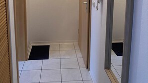 A narrow hallway with a tiled floor, wooden doors, and a mirror on the right. - FW Muschel - House Seewind Warnemünde - Object 25830 (Rostock)