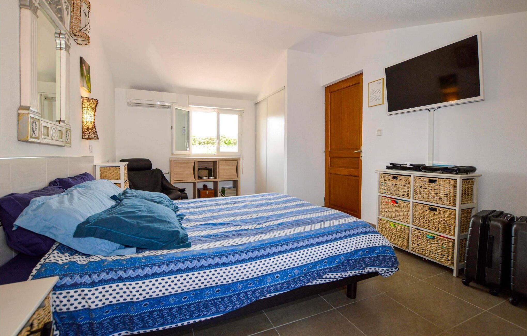 A bedroom with a bed, a TV, a wardrobe, and a desk with a chair.