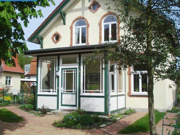 Ett tvåvåningshus med en balkong, en ytterdörr och en liten veranda.