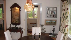 A dining area with a round table, chairs, a chandelier, a mirror, and a wall with framed items. - 3 bedroom beautiful home in Trosa (Trosa)