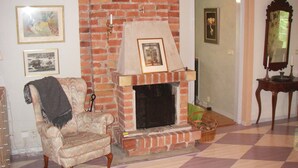 A living room with a brick fireplace, a patterned armchair, and a checkered floor. - 3 bedroom beautiful home in Trosa (Trosa)