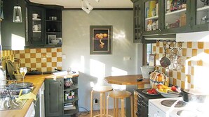 A kitchen with a wooden countertop, a stove, and a sink. There are two stools and a framed picture on the wall. - 3 bedroom beautiful home in Trosa (Trosa)
