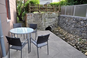 A patio with a round table and four chairs, a stone wall, and a wooden fence.