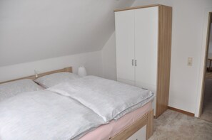 A bedroom with a bed, a wardrobe, and a small bedside table.