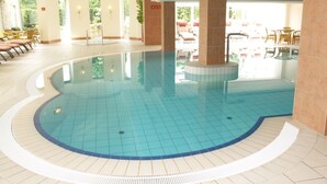 A large indoor swimming pool with tiled flooring and a curved edge.