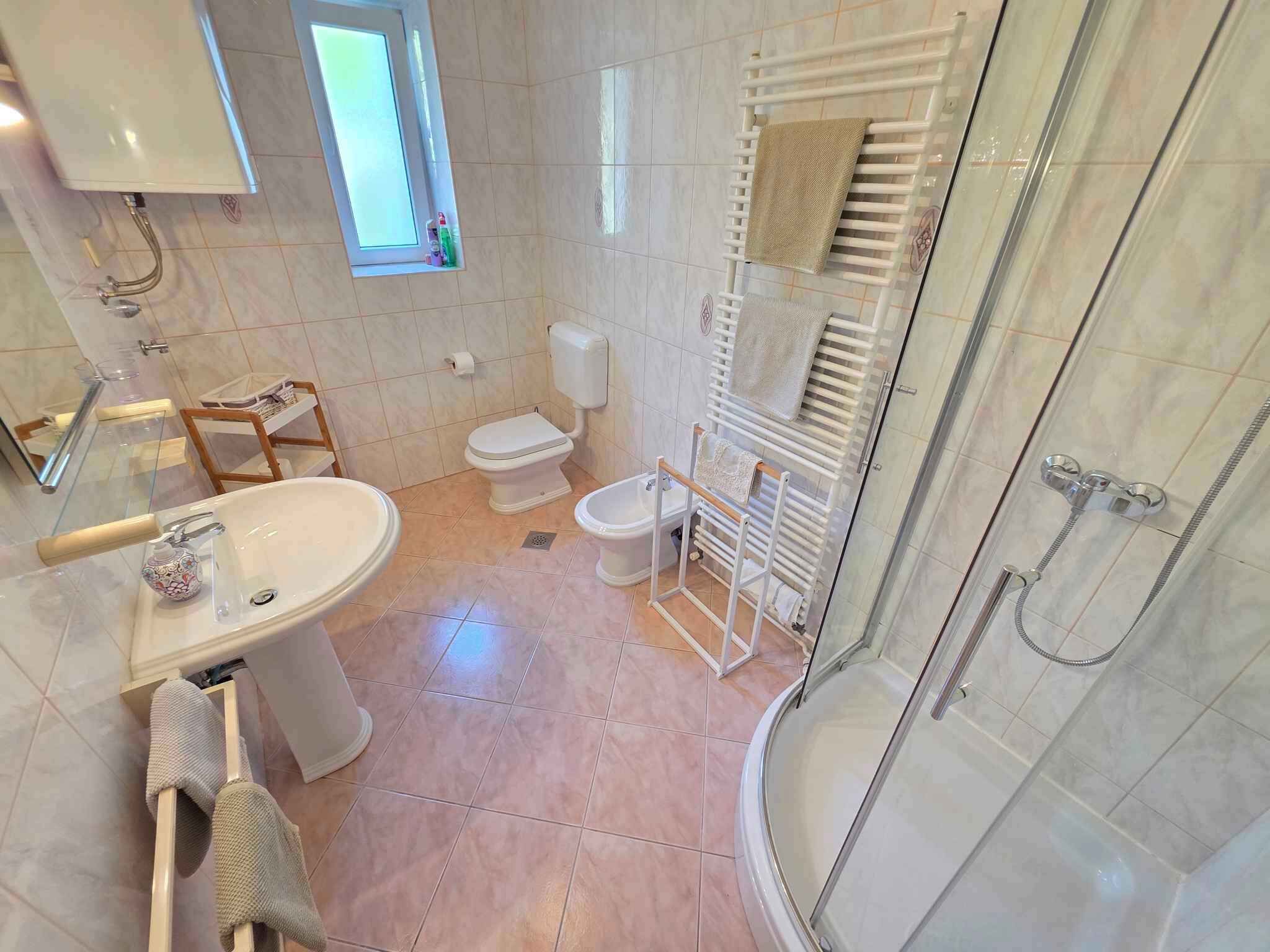 A bathroom with a sink, toilet, shower, and towel rack.