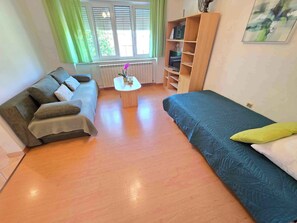 Une pièce comprenant un canapé, un lit, une petite table et une bibliothèque.