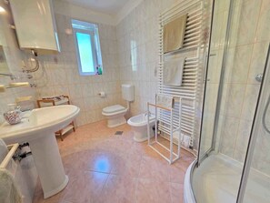Ein Badezimmer mit Waschbecken, Toilette, Bidet und Dusche.