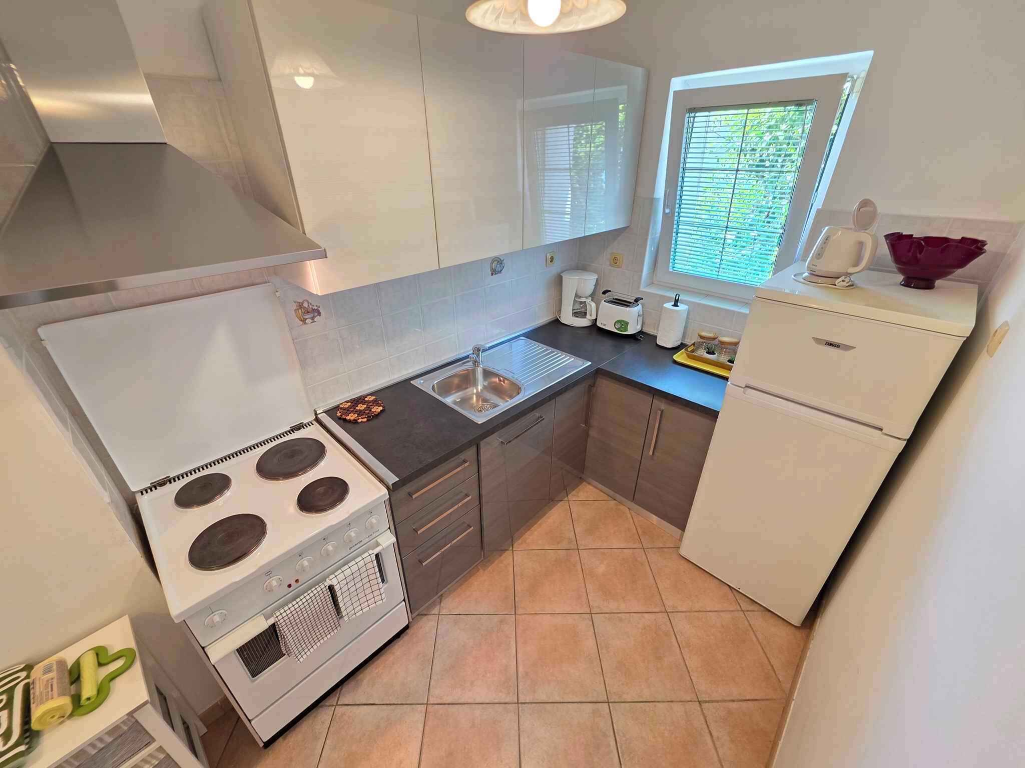 Una cucina compatta con piano cottura, forno, lavello e frigorifero.