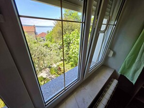 A room with a large window, a radiator, and a green towel hanging on the wall.
