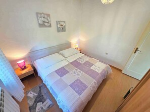Ein Schlafzimmer mit einem Bett, zwei Wandleuchten, einer Tür und einem kleinen Teppich.