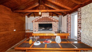 A rustic wooden interior with a brick oven and a dining table set for four. - Stunning home in Radasinovci (Radasinovci)