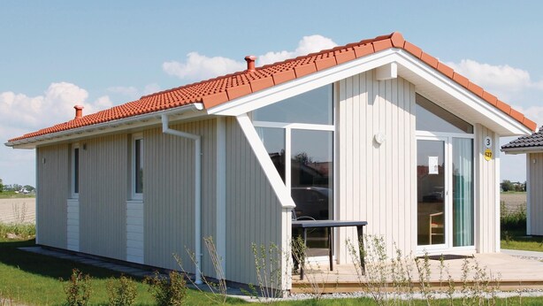 Un bâtiment moderne de plain-pied, doté d’un toit en pente, de grandes fenêtres et d’un petit espace porche.