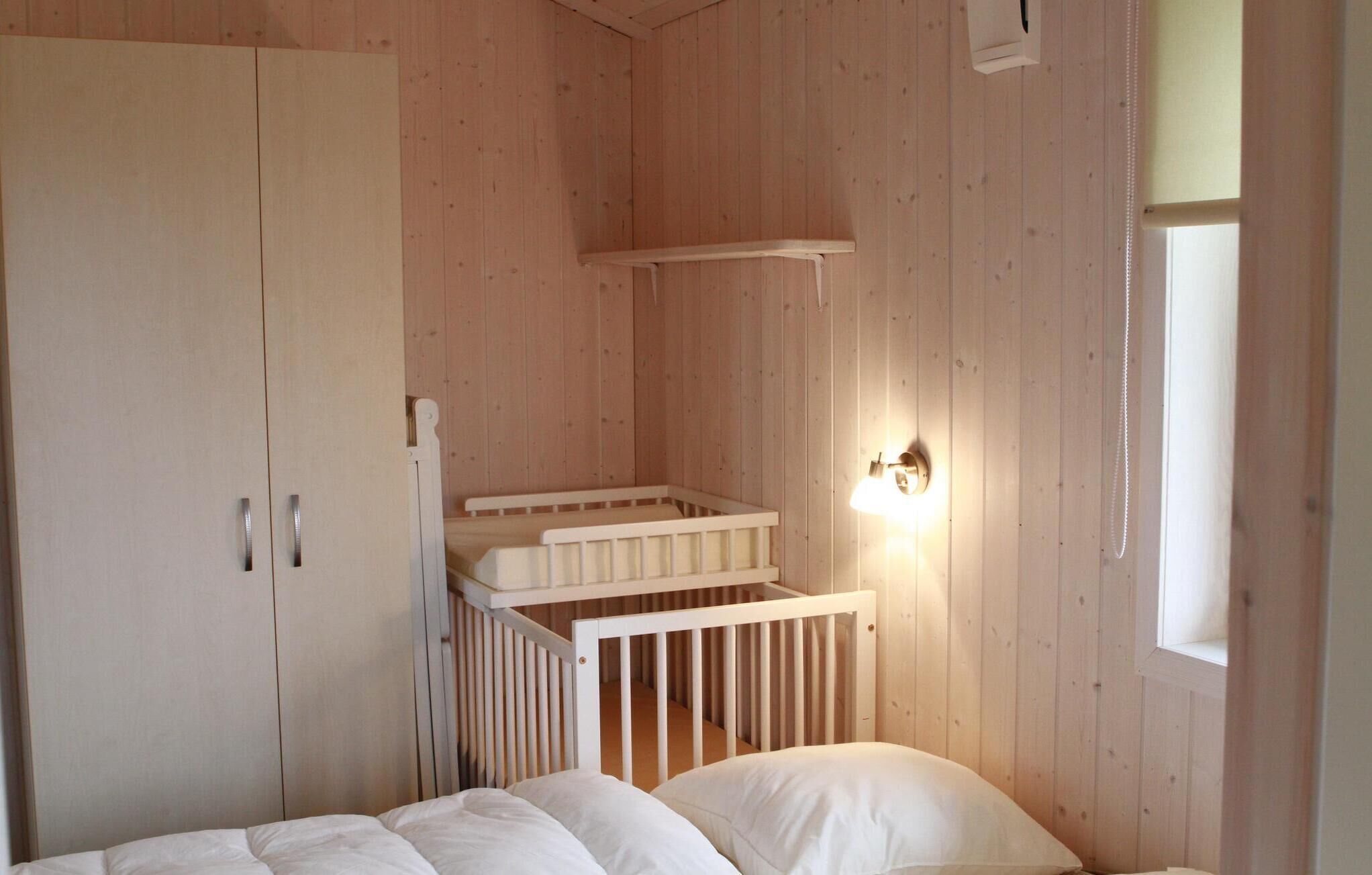 A wooden room with a crib, a bed, and a wardrobe.